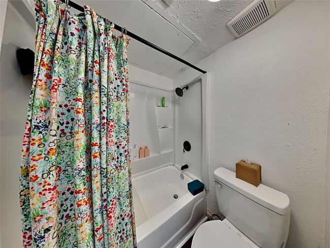 Bathroom with shower / tub combo with curtain, a textured wall, and a textured ceiling | Image 14