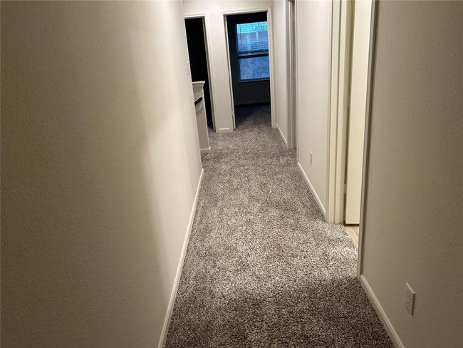 Corridor featuring a textured wall, baseboards, and light carpet | Image 6