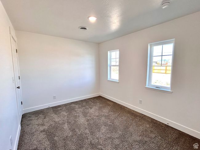 Spare room with visible vents, dark colored carpet, and baseboards | Image 12