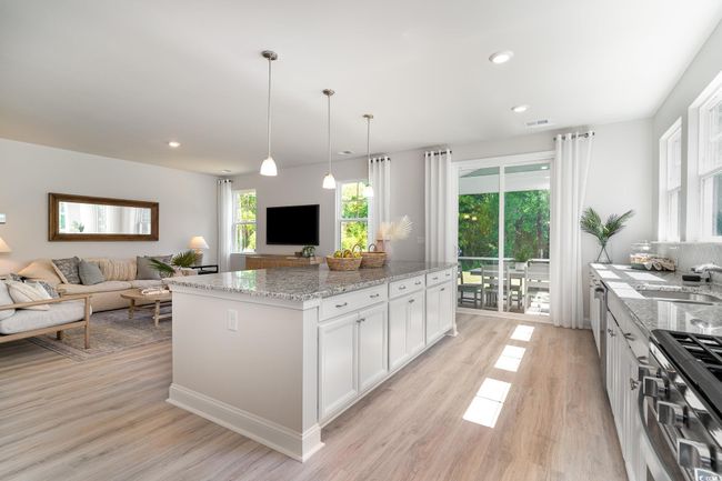 Kitchen with light stone counters, open floor plan, white cabinetry, and stainless steel gas range | Image 5