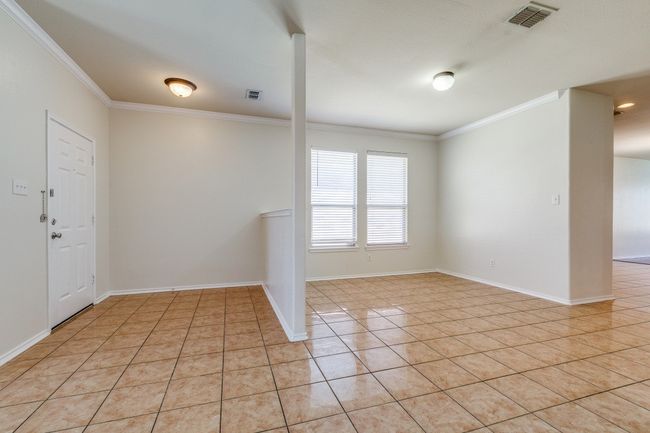 Empty room featuring light tile patterned floors, visible vents, baseboards, and ornamental molding | Image 13
