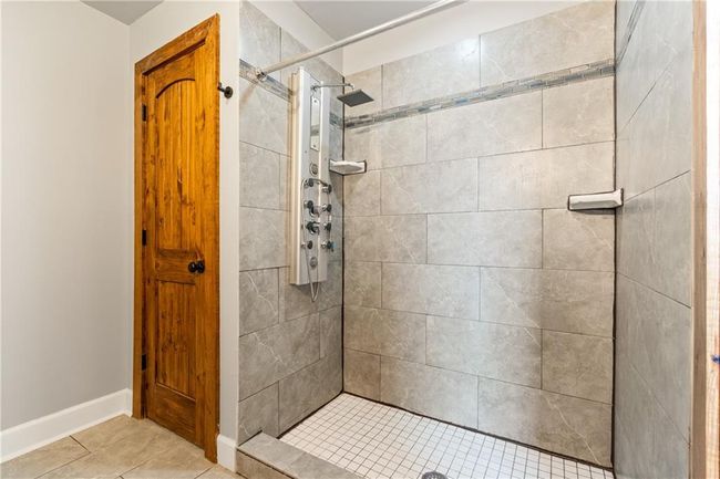 Bathroom with a tile shower and tile patterned floors | Image 15