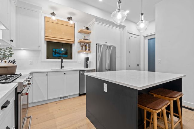 Kitchen featuring visible vents, light wood finished floors, a sink, high quality appliances, and tasteful backsplash | Image 11