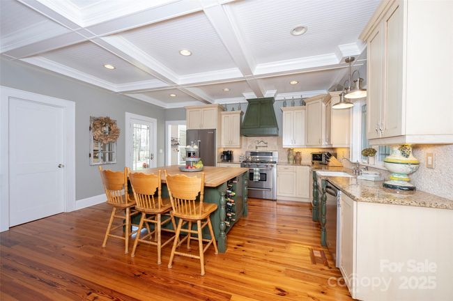 The center island has a butcher block countertop, wine rack, microwave cabinet, and breakfast bar. | Image 9