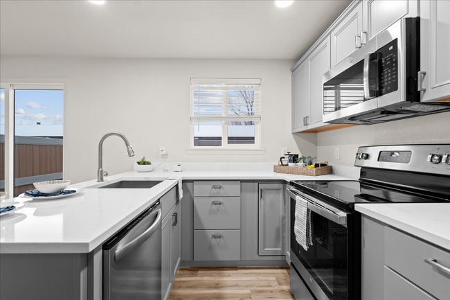 Kitchen featuring appliances with stainless steel finishes, gray cabinetry, a peninsula, light countertops, and recessed lighting | Image 8