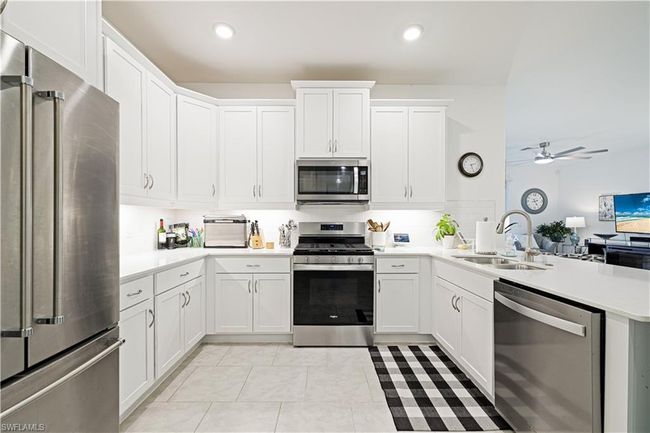 Kitchen featuring stainless steel appliances, a peninsula, light countertops, ceiling fan, and white cabinetry | Image 13