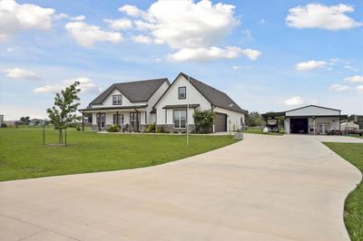 Driveway leading to 2 car garage and large metal building. | Image 2