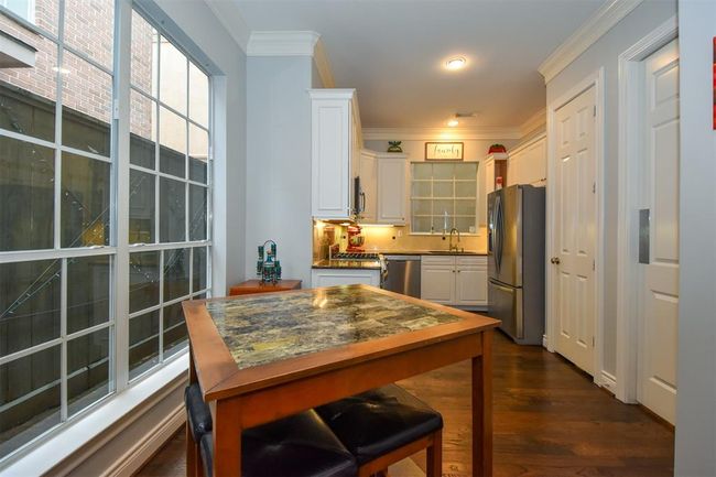 Kitchen featuring white cabinetry, stainless steel appliances, ample natural light from large windows, and a dine-in area | Image 12