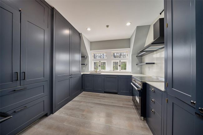 Kitchen with light wood-type flooring, electric range oven, open shelves, and a sink | Image 17