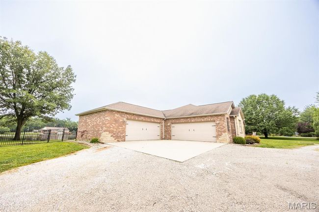 View of front of home featuring gravel driveway, brick siding, and an attached garage | Image 9