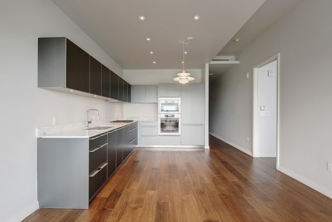 Kitchen with a sink, modern cabinets, light countertops, wood finished floors, and baseboards | Image 9