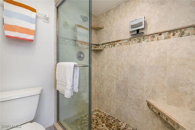 OWNER'S SUITE SHOWER. FULL-HEIGHT TILED WALLS WITH DECORATIVE BORDER. BUILT-IN SHELVES AND SEAT. GLASS SLIDING DOORS. | Image 18