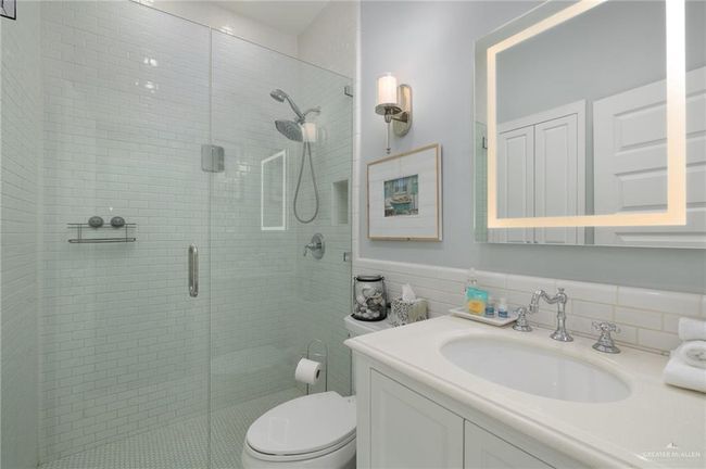 Bathroom featuring tile walls, vanity, a shower with shower door, and toilet | Image 10