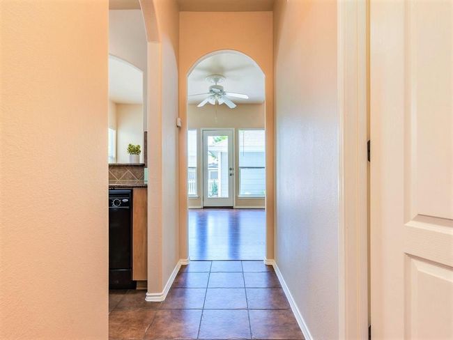 The entry hallway opens into the kitchen and continues through a sweeping archway into the main living area. | Image 9