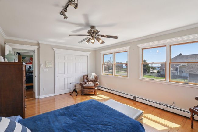 Bedroom with crown molding, a closet, baseboard heating, wood finished floors, and baseboards | Image 21
