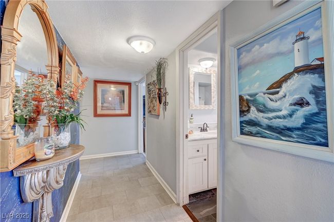 Hallway with a textured ceiling, baseboards, and light tile patterned floors | Image 21