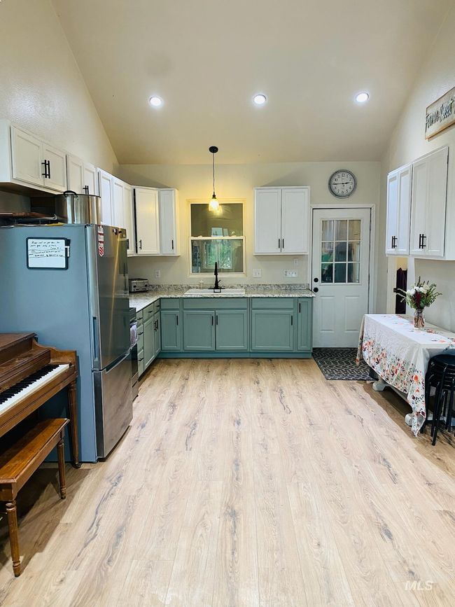 Kitchen featuring freestanding refrigerator, vaulted ceiling, light countertops, light wood-style floors, and green cabinets | Image 12