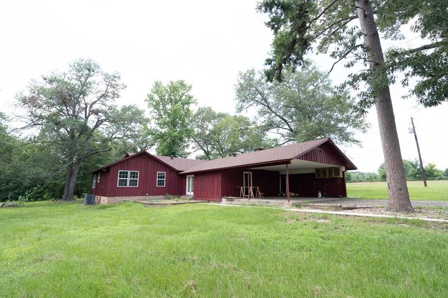 Back of house featuring an attached carport, a lawn, driveway, and board and batten siding | Image 34
