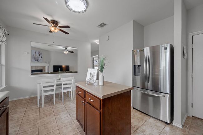 Kitchen with stainless steel fridge with ice dispenser, ceiling fan, light countertops, light tile patterned floors, and open floor plan | Image 14