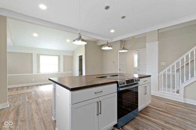 kitchen with butcher block counters, stainless steel electric stove, light wood-style floors, decorative light fixtures, and recessed lighting | Image 15