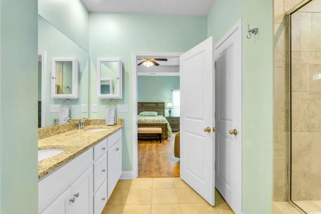 Ensuite bathroom featuring a sink, a ceiling fan, a shower stall, connected bathroom, and tile patterned flooring | Image 21