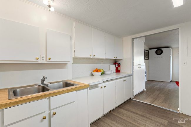 Kitchen featuring light countertops, white cabinetry, light wood-style flooring, and a textured ceiling | Image 9