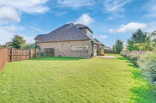 View of side of home featuring a shingled roof, a fenced backyard, brick siding, and a patio | Image 37