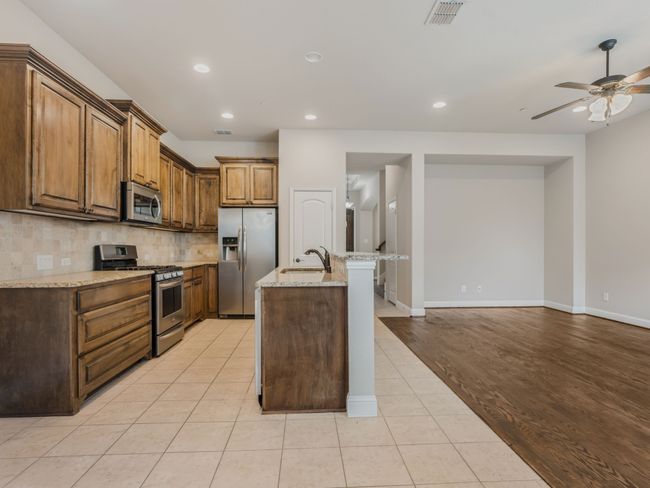 Kitchen with appliances with stainless steel finishes, backsplash, a ceiling fan, recessed lighting, and light stone countertops | Image 17