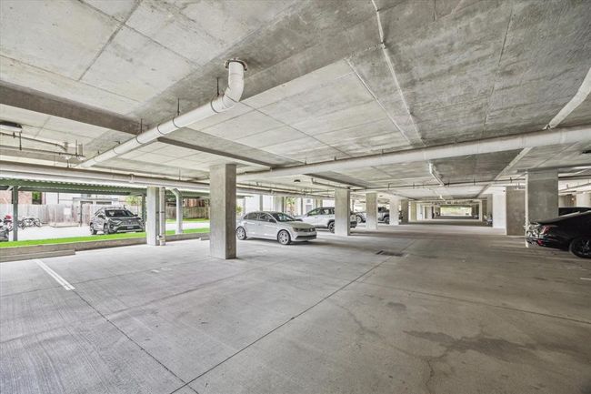 Gated garage with controlled access entry, offering peace of mind and convenience to residents. The well-lit space features clearly marked spots, allowing easy navigation and parking. | Image 19