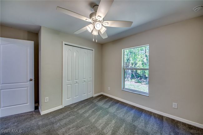 Unfurnished bedroom with a ceiling fan, dark colored carpet, a closet, and baseboards | Image 40