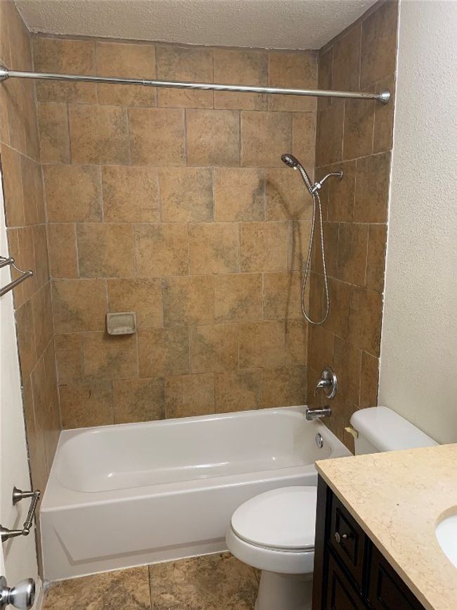 Bathroom with toilet, vanity, washtub / shower combination, and a textured ceiling | Image 10