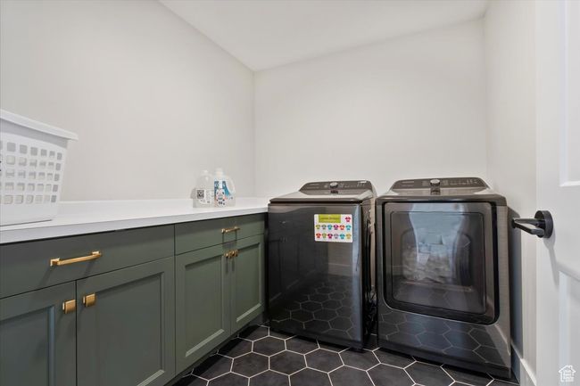 Washroom with washing machine and dryer, dark tile patterned floors, and cabinet space | Image 33