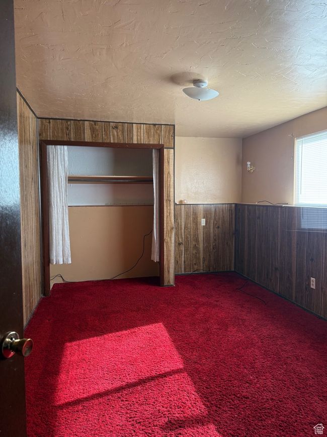 Spare room with a wainscoted wall, wood walls, carpet, and a textured ceiling | Image 25