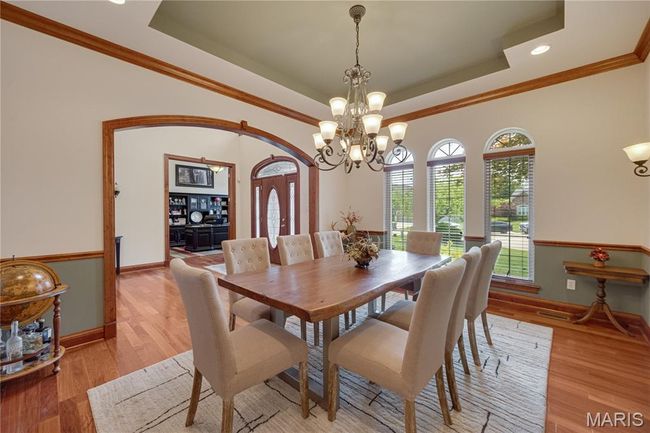 Dining space with a raised ceiling, a chandelier, light wood-style flooring, crown molding, and recessed lighting | Image 41