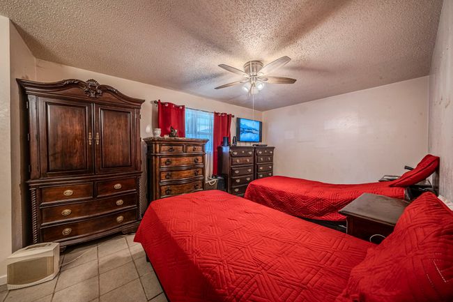 Bedroom with a textured ceiling, light tile patterned floors, and a ceiling fan | Image 15
