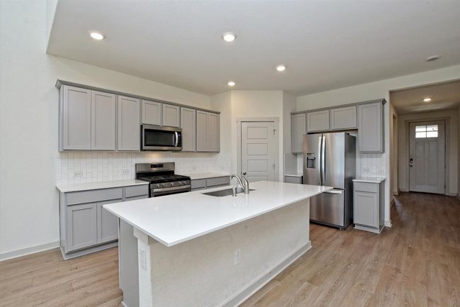 Kitchen with stainless steel appliances, a sink, gray cabinets, light wood-type flooring, and recessed lighting | Image 10