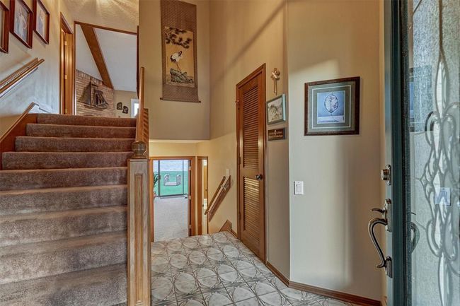 The entry door opens to a foyer with stairs leading to both the first and second levels, with a coat closet just beyond offering additional storage. | Image 7