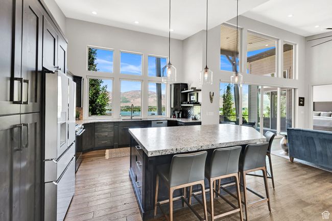 Kitchen featuring a high ceiling, GE Cafe Platinum Glass appliances, light wood-flooring, a kitchen island, and a sink | Image 25