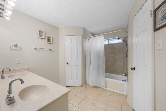 Bathroom with tile patterned floors, shower / tub combo with curtain, a textured ceiling, and double vanity | Image 10