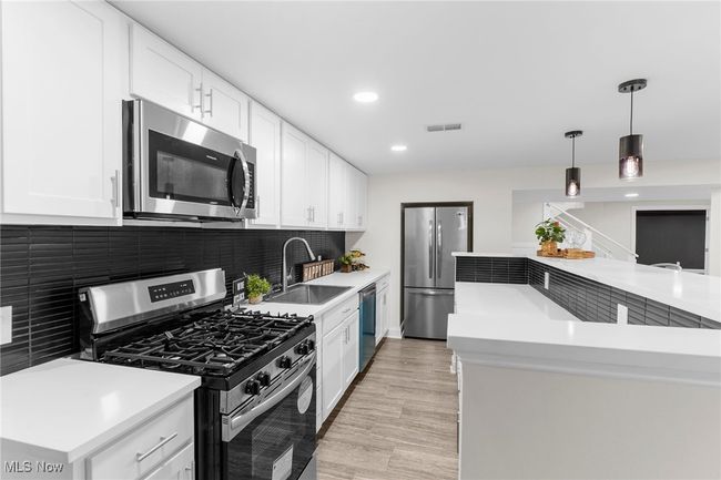 Kitchen with stainless steel appliances, tasteful backsplash, light countertops, hanging light fixtures, and recessed lighting | Image 33