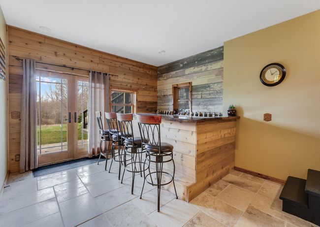 Lower level entertaining space with a beautiful custom bar, stone tile floors, patio doors leading out to a concrete patio | Image 40