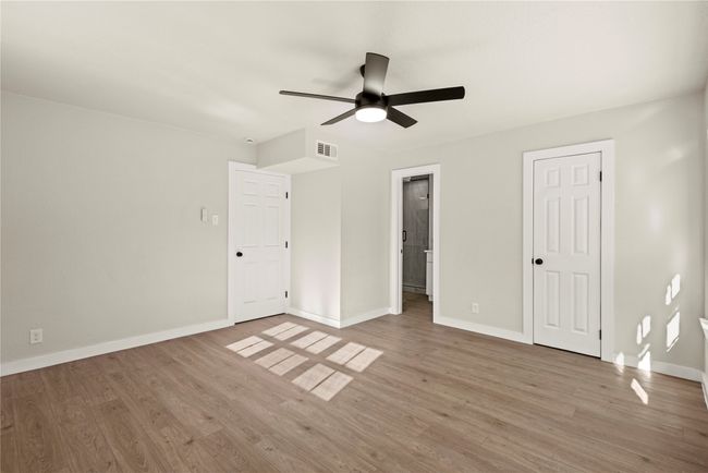 Unfurnished bedroom with light wood finished floors, visible vents, baseboards, and connected bathroom | Image 18