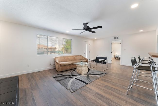 Living area with baseboards, visible vents, wood finished floors, and a ceiling fan | Image 14