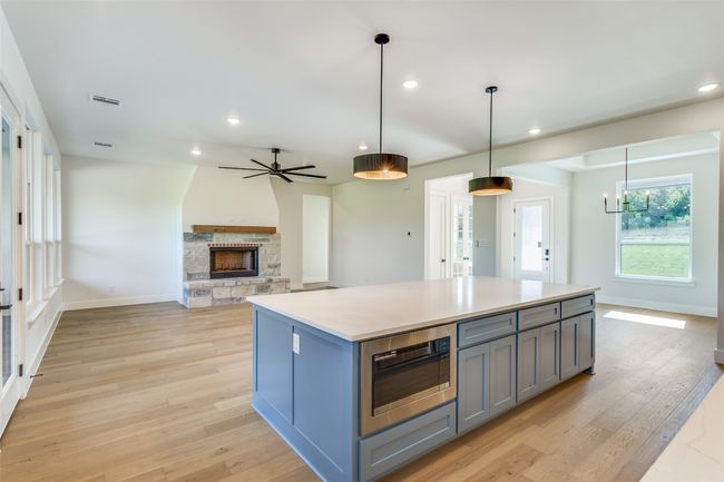 Kitchen featuring stainless steel microwave, light wood-type flooring, a kitchen island, gray cabinetry, and visible vents | Image 5