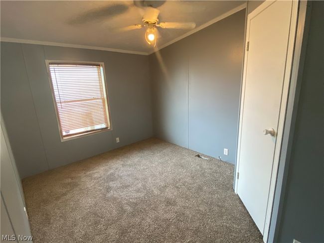 Empty room with ceiling fan, ornamental molding, carpet floors, and a wealth of natural light | Image 7