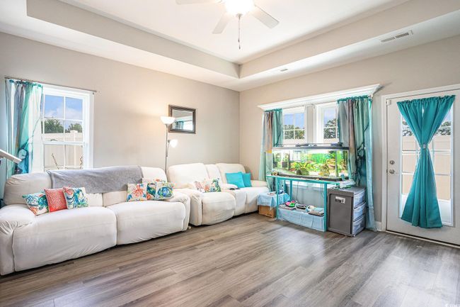Living room featuring wood finished floors, a ceiling fan, and a raised ceiling | Image 4