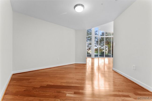 Spare room featuring light wood finished floors, a wall of windows, and baseboards | Image 17
