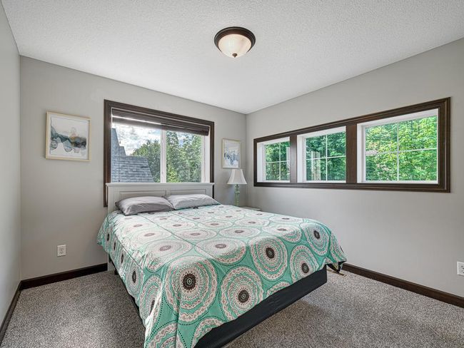 The fourth of four bedrooms on the upper level. Lots of natural light through two banks of windows. This room would also make an excellent office or craft room, with a low table or desk beneath the piano windows. | Image 26