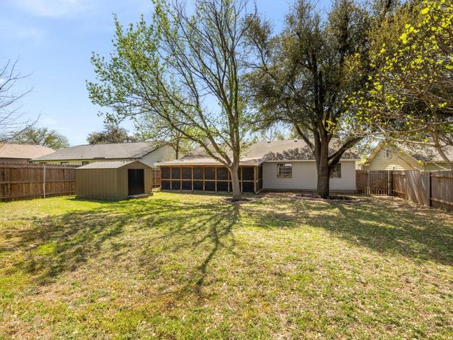 View of yard featuring a sunroom, an outbuilding, a fenced backyard, and a storage shed | Image 25