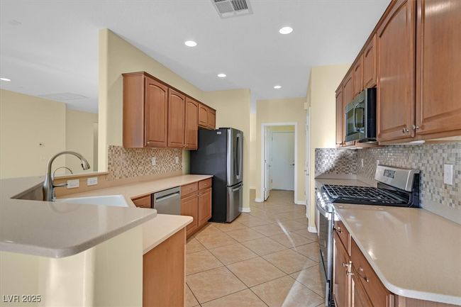 Kitchen featuring appliances with stainless steel finishes, a peninsula, light countertops, and tile backsplash | Image 10